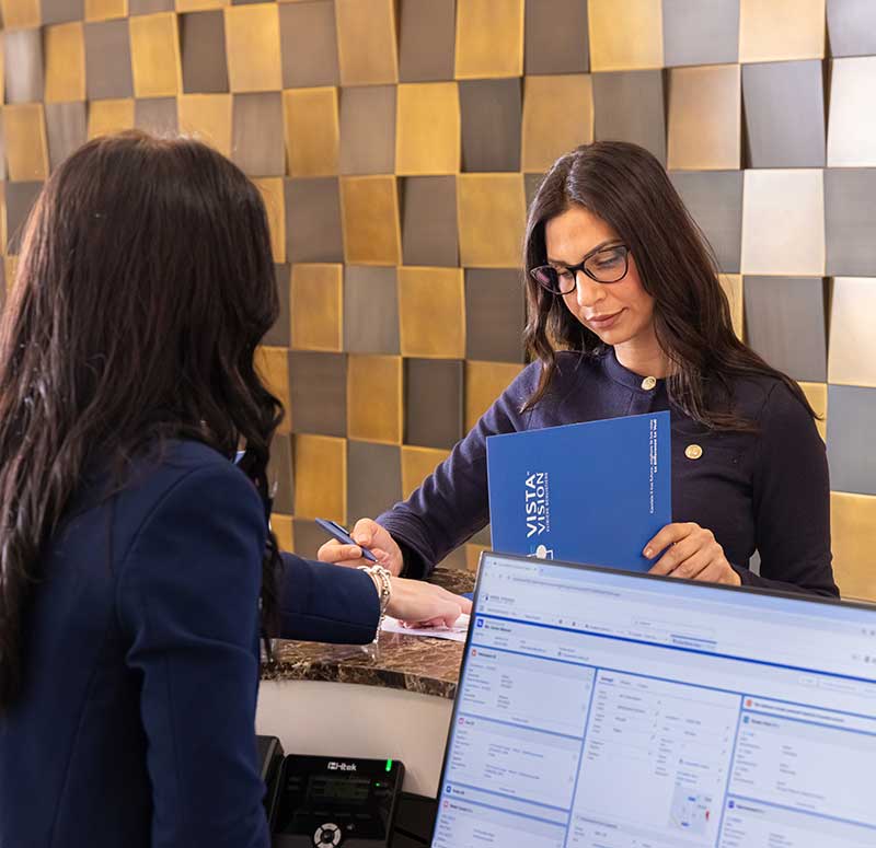 Il team di Vista Vision mostra ad una donna le convenzioni assicurative per l'operazione agli occhi